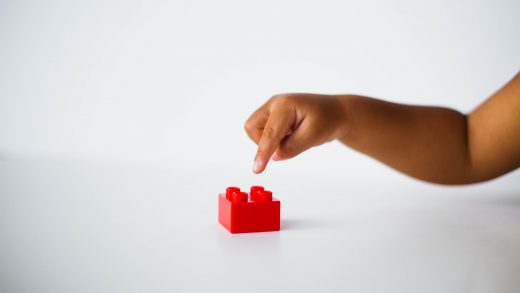 child pointing to red interlocking brick toy